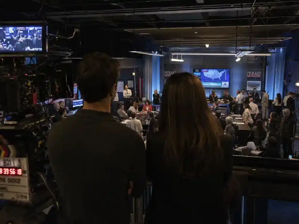 Succession cast and characters guide Shiv and Roman — sibling actor silhouettes from behind at campaign war room TV drama film set with monitors