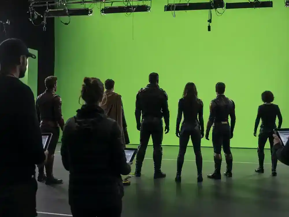 Superman 2026 movie cast and characters guide DCU heroes — ensemble cast silhouettes rehearsing on green-screen superhero film stage from behind