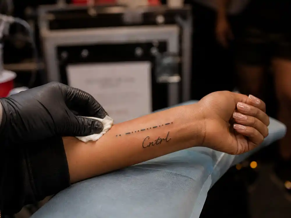 SZA tattoos and their meanings SOS — Morse code SOS and Cntrl wrist tattoos backstage with tattoo artist gloved hand