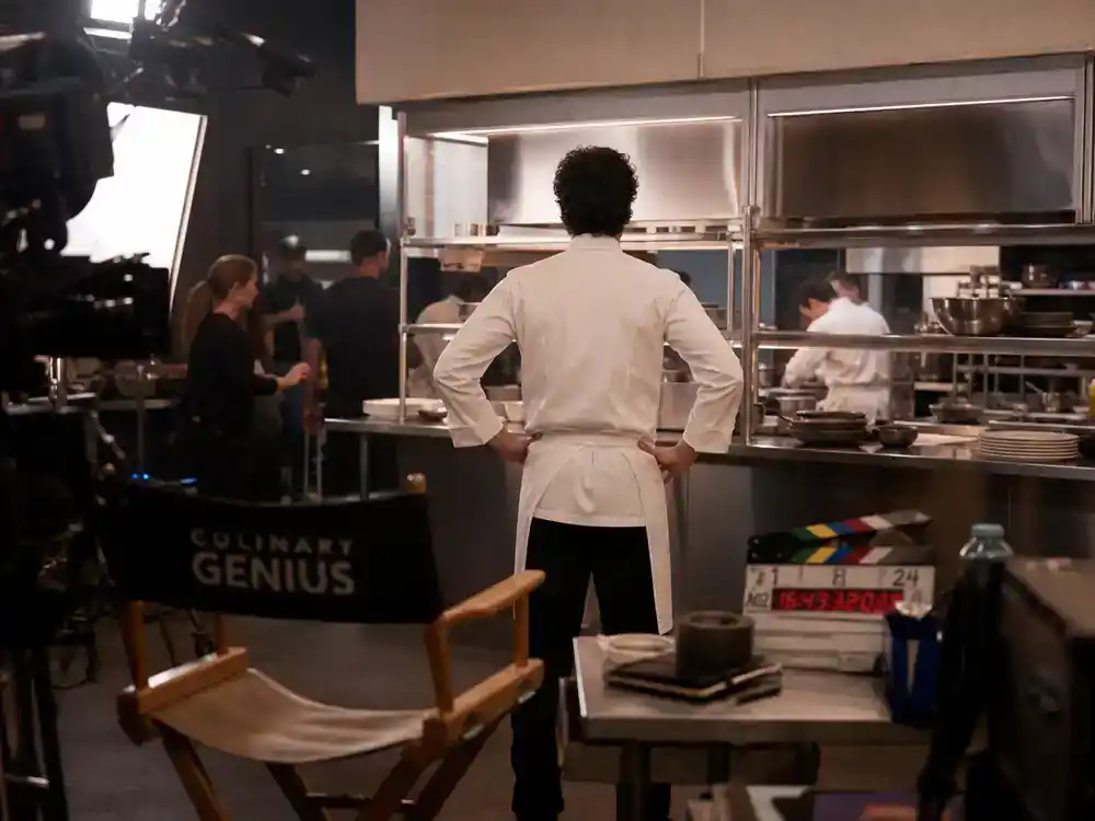 The Bear season 4 cast and kitchen guide Carmy — lead chef actor silhouette from behind on restaurant TV drama set with director chair and clapperboard