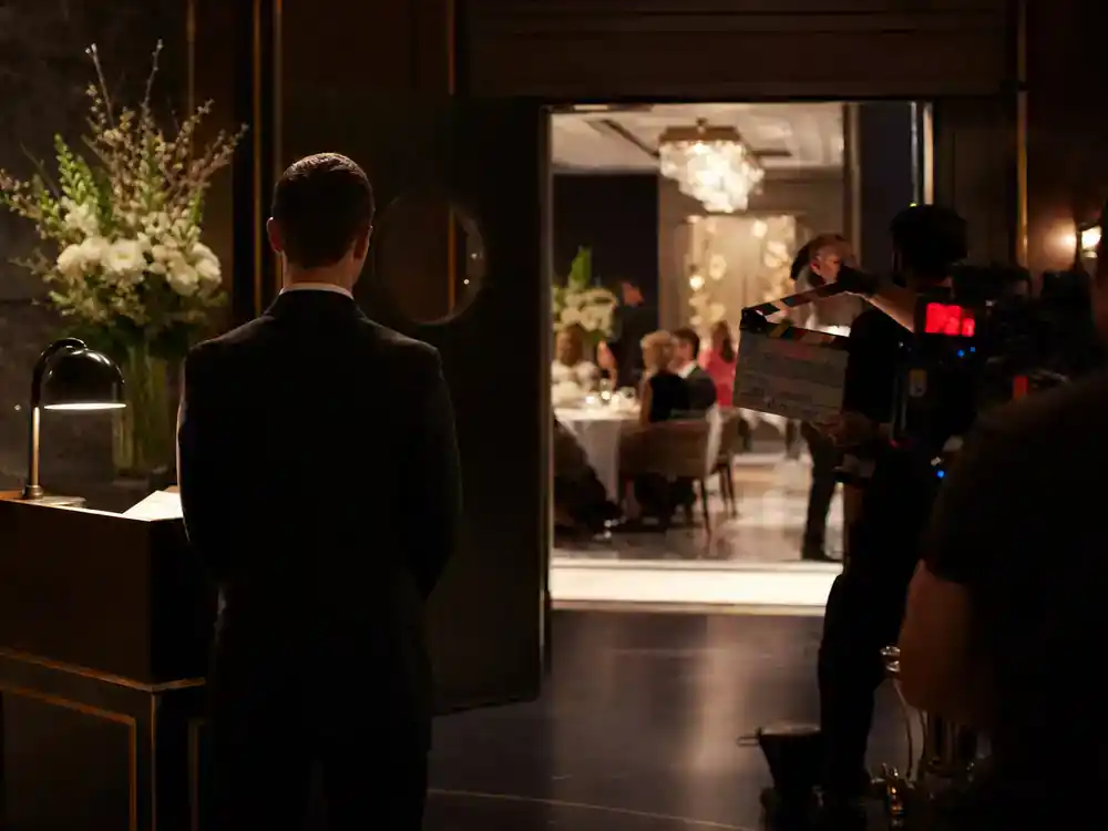 The Bear season 4 cast and kitchen guide Richie — front-of-house actor silhouette from behind on upscale restaurant TV drama film set with dining room visible