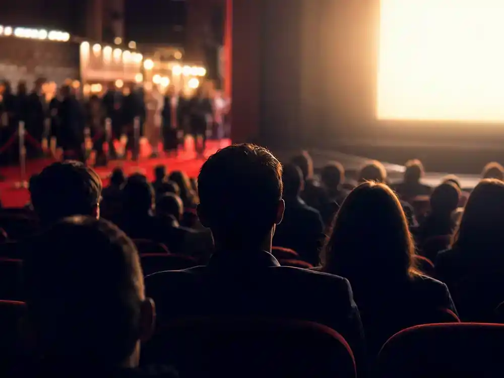 The Odyssey 2026 movie cast and plot explained release — theater marquee with July premiere date and ticket-buyer silhouettes at evening box office