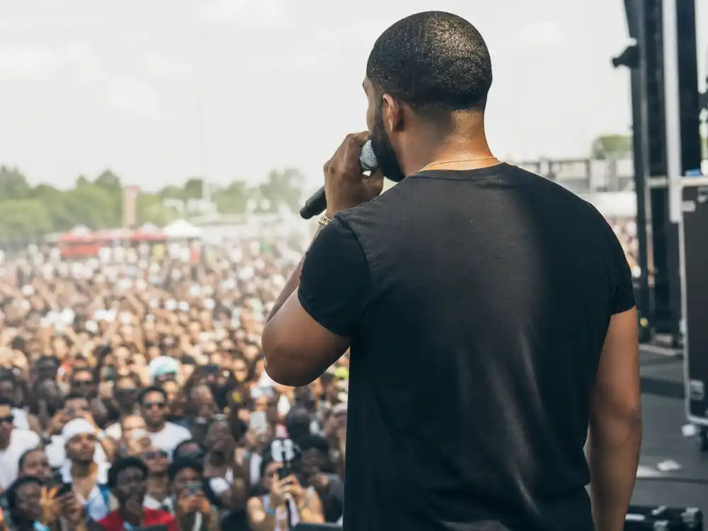 The Weeknd tattoos and their meanings — festival performance from behind showing bare uninked arms on R&B artist in short sleeves