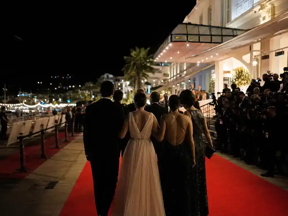 The White Lotus season 4 cast and location guide premiere — film festival red carpet with cast silhouettes and photographers at coastal hotel evening event