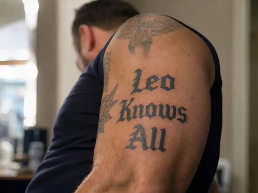 Tom Hardy tattoos and their meanings — Leo Knows All block-letter bicep tattoo from DiCaprio Oscar bet close-up