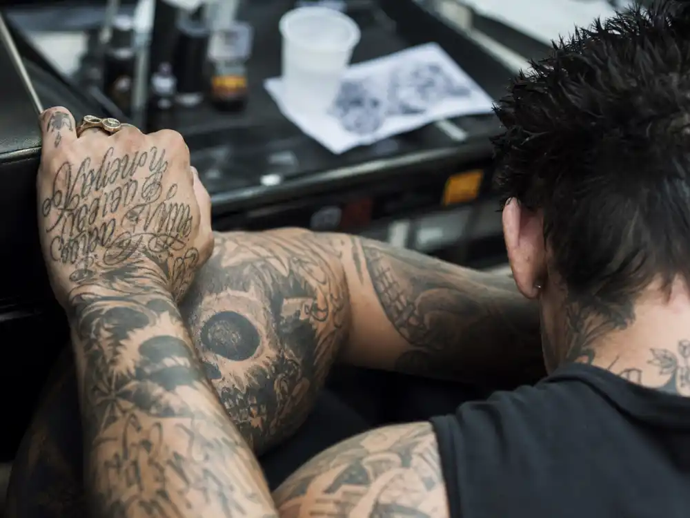 Travis Barker tattoos and their meanings — close-up of heavily tattooed forearm sleeve with skull and script motifs on punk musician