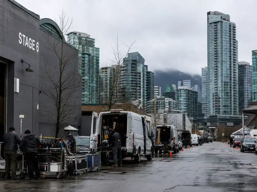 Twilight movies filming locations guide Vancouver BC — film studio exterior with production vans and crew unloading equipment near urban skyline