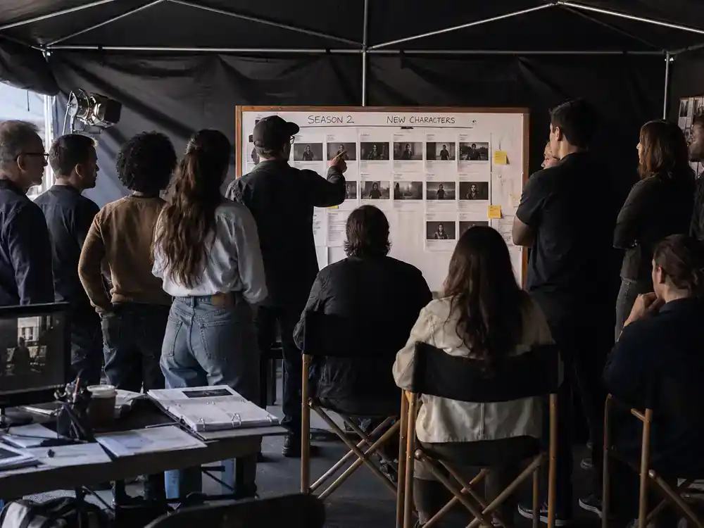 Wednesday season 2 cast and new characters guide new faces — veteran actor silhouettes meeting younger cast in production tent from behind on Ireland film set