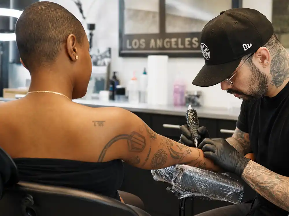 Willow Smith tattoos and their meanings — tattoo artist inking forearm during professional Los Angeles studio session from behind