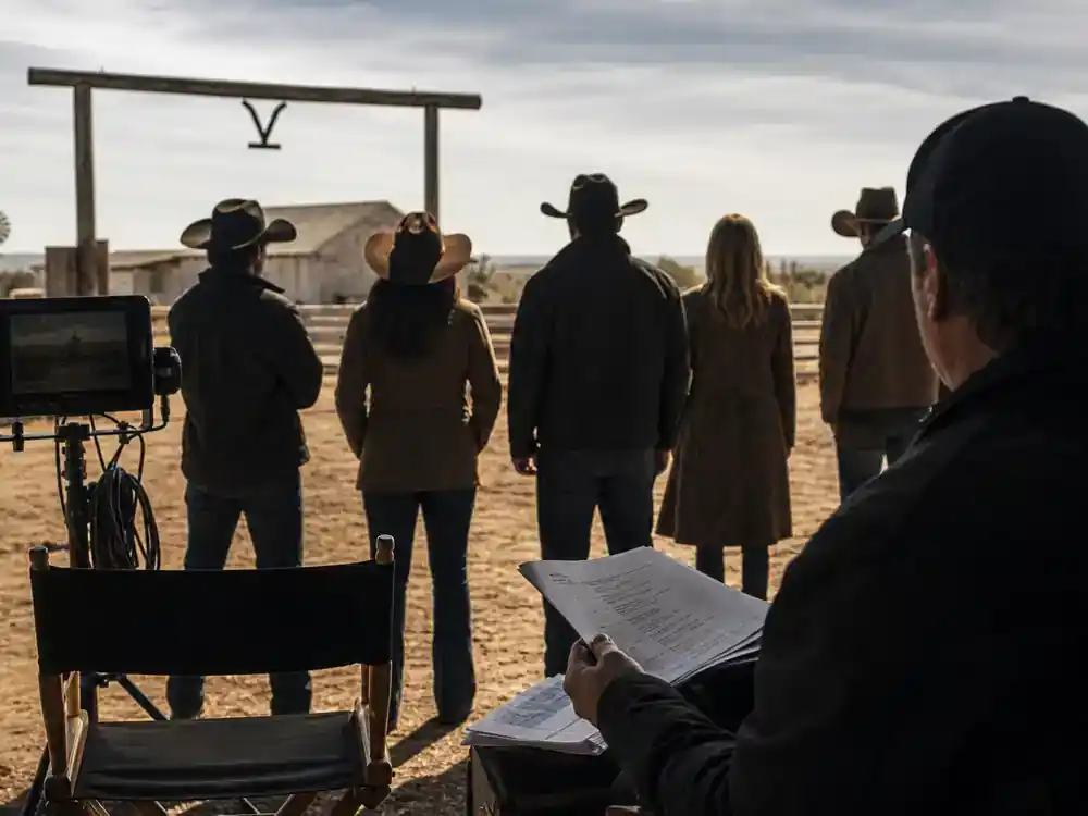 Yellowstone spinoff 2026 cast and timeline guide Dutton Ranch — Beth and Rip spinoff cast silhouettes from behind on South Texas ranch TV production set with director monitor