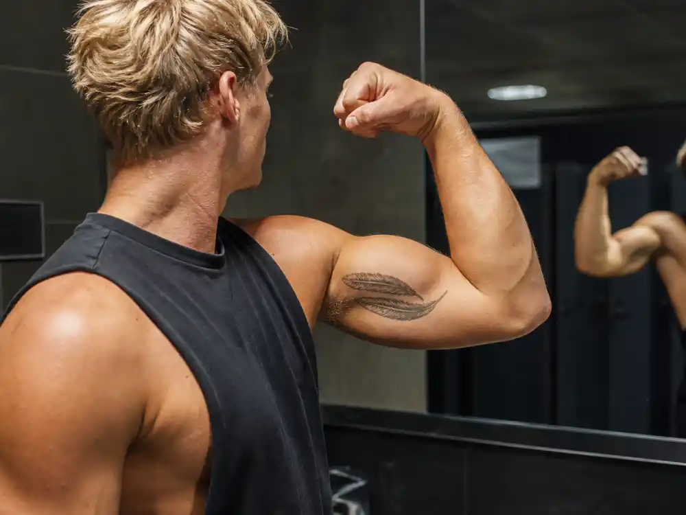 Zac Efron tattoos and their meanings — double feather tattoo on inner right bicep during Men's Health magazine fitness photoshoot