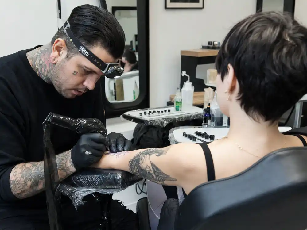Zoe Kravitz tattoos and their meanings — Dr Woo style fine-line tattoo artist inking eagle forearm piece during professional studio session