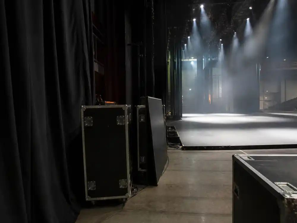Empty arena stage viewed from the backstage wing, illustrating why Billie Eilish net worth 2026 is not the same as tour gross
