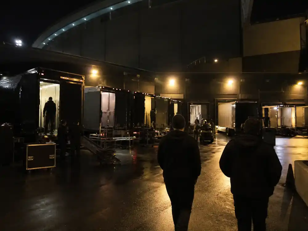 Arena loading dock at night with departing tour trucks, the second tour peak on Billie Eilish net worth over the years