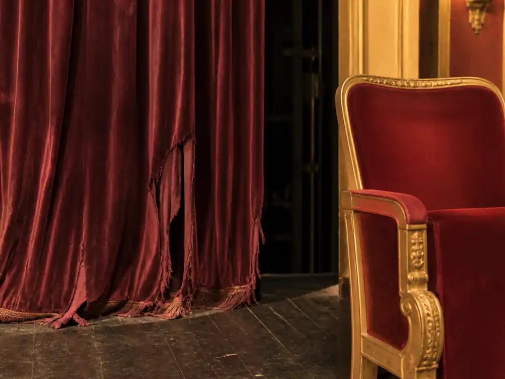 Faded stage curtain beside fresh theater seat evoking Bruno Mars net worth over the years plateau