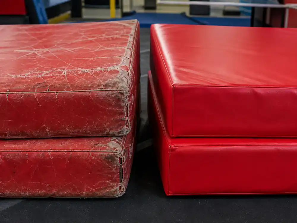 Worn crash pads versus new pads in a stunt gym reflecting Dwayne Johnson net worth over the years as fees climbed