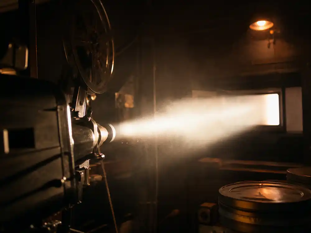 Empty cinema projection booth with a light beam, a concert-film revenue stream in how Beyonce makes money