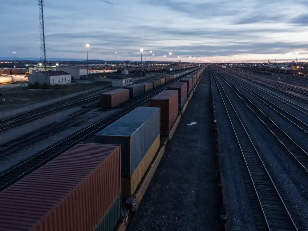 Freight rail yard at dusk showing how Bill Gates makes money from industrial holdings