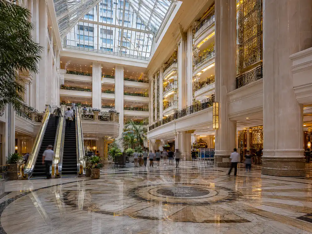 Grand hotel atrium with distant figures, a wealth-scale contrast for how much is Billie Eilish worth against billionaire peers